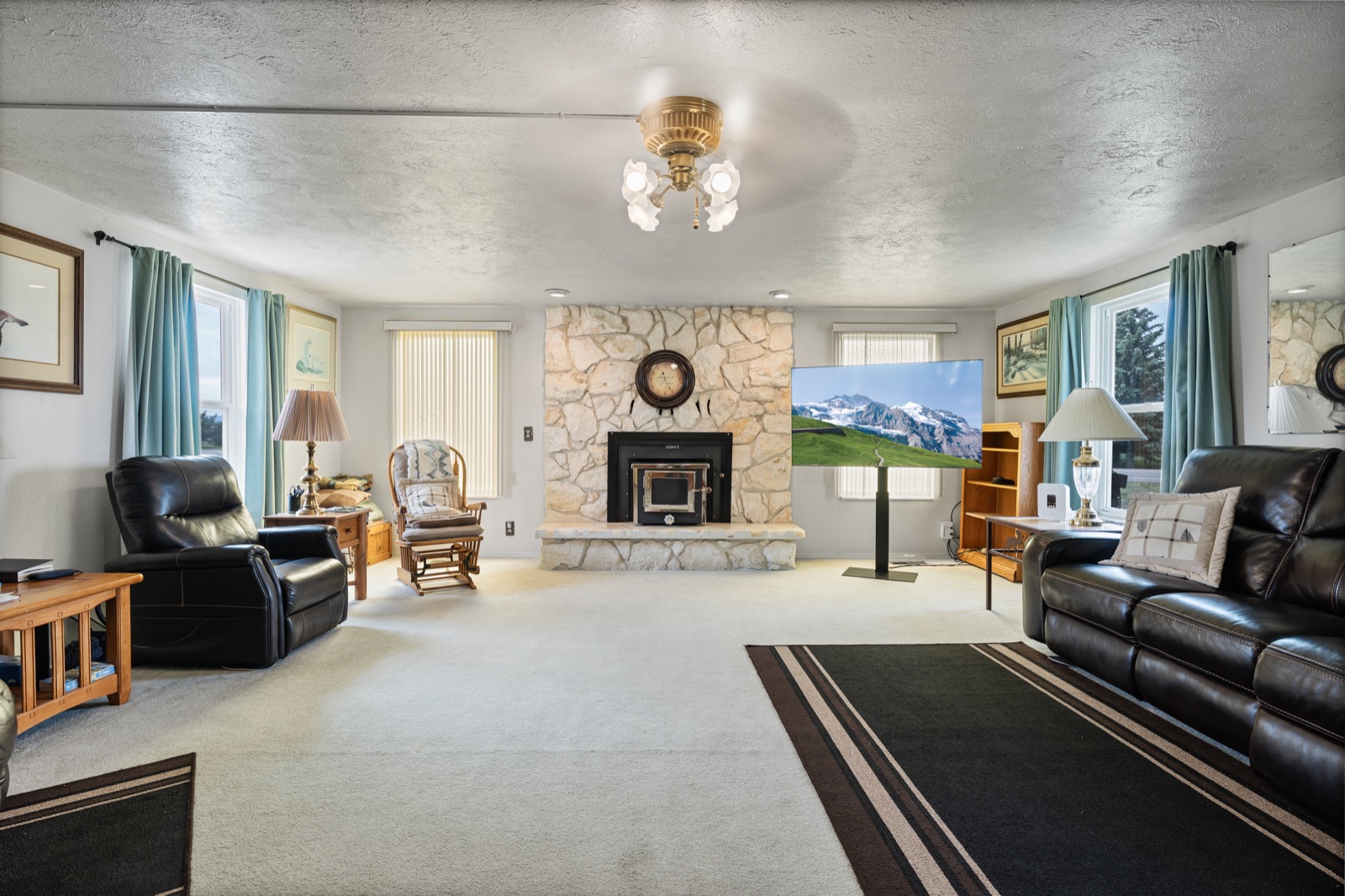 Spacious living room with floor-to-ceiling stone fireplace and mountain views