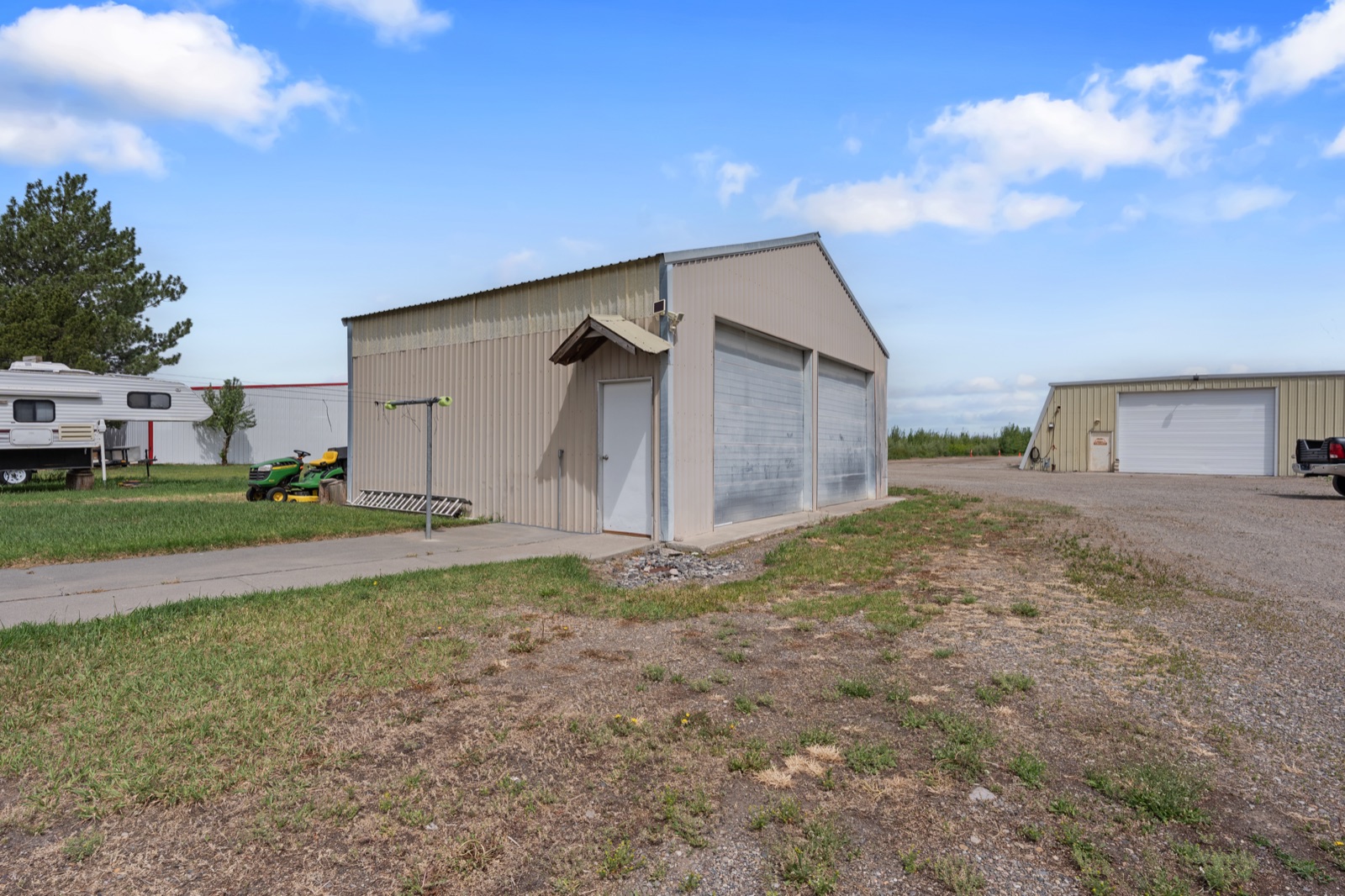Large detached metal shop with RV parking beside the home